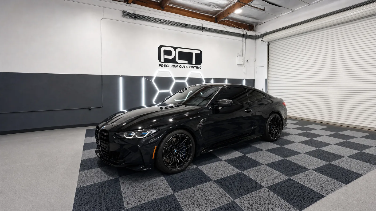 A gloss black BMW M4 Competition with fresh window tint in our studio