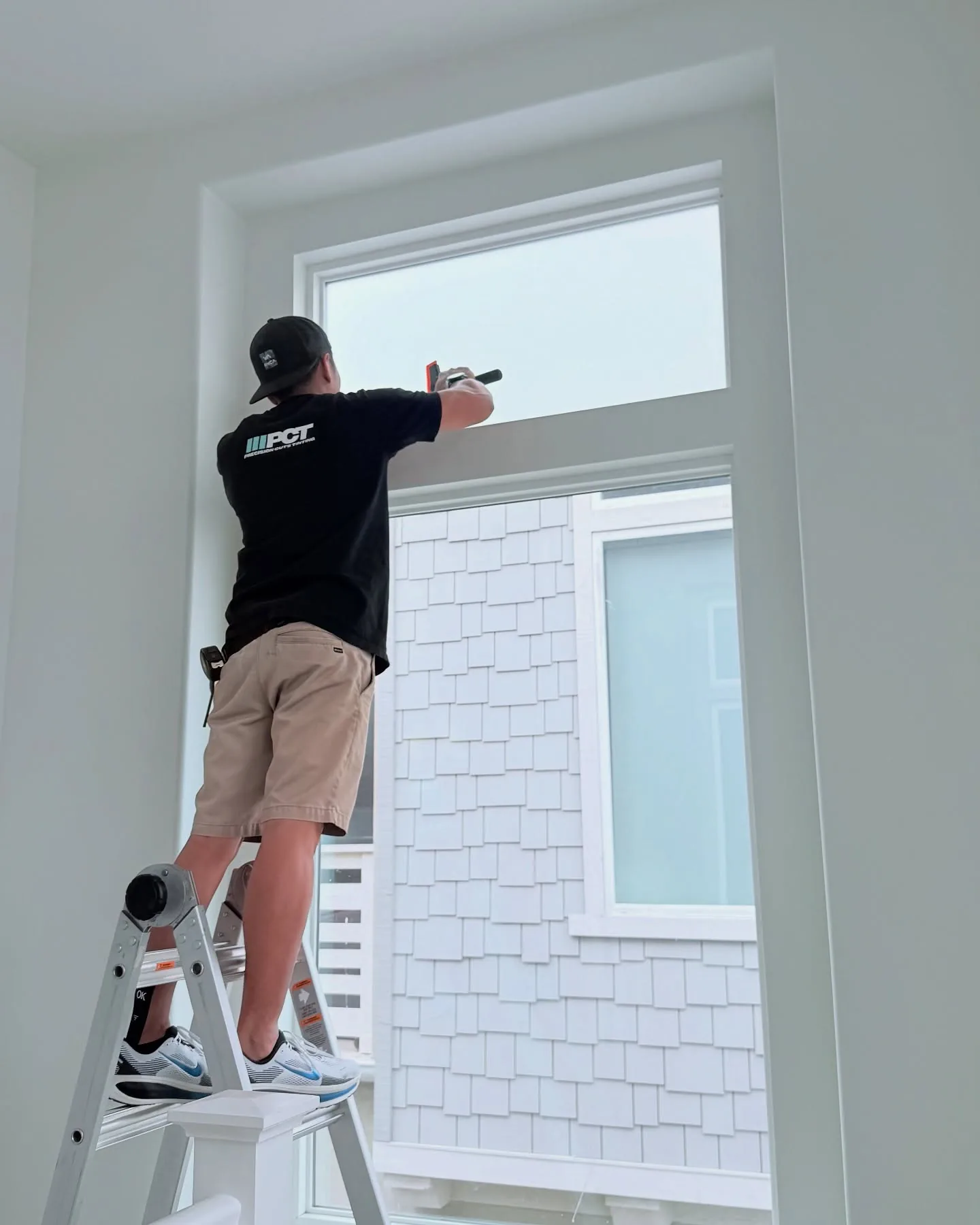 One of our installers fitting window film on a home’s tall window
