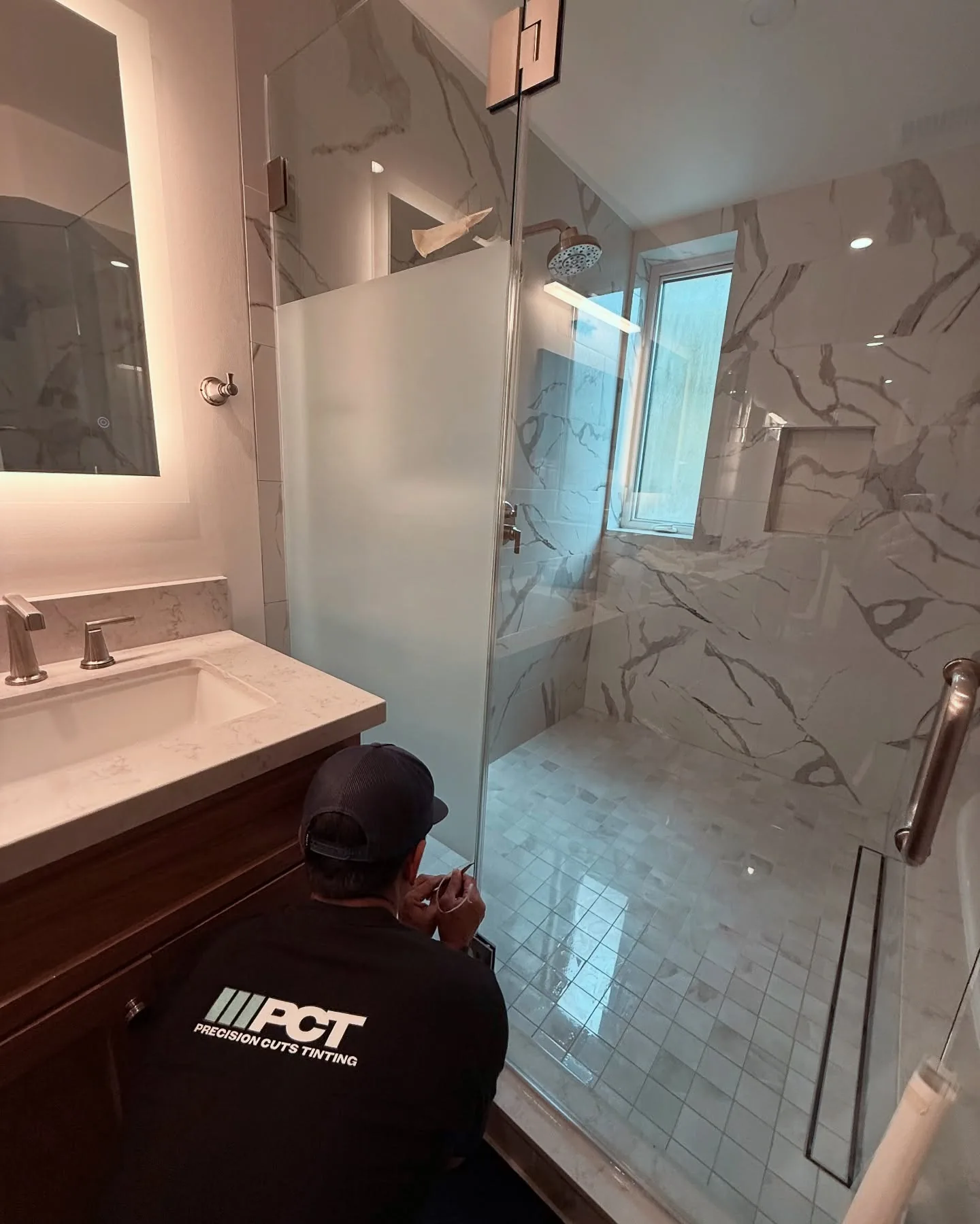 One of our installers fitting privacy film to shower glass