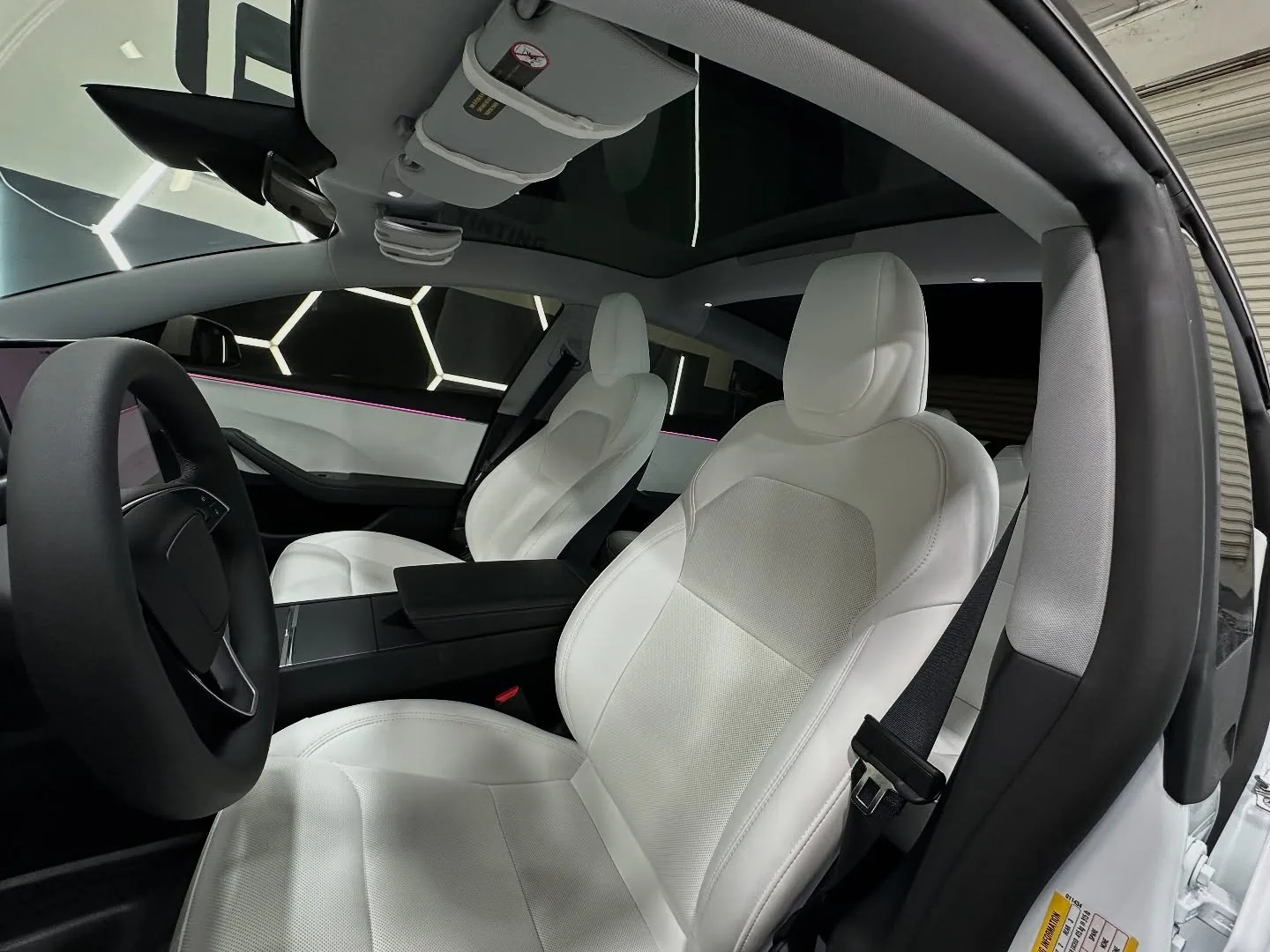 Inside a white Tesla Model 3 we tinted, its glass roof filmed